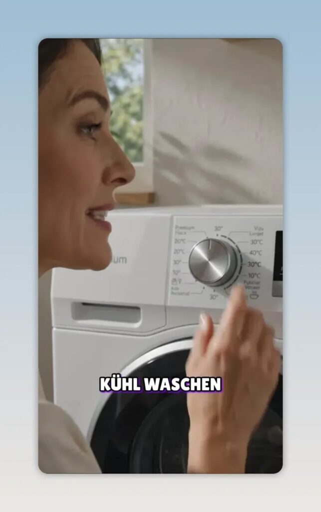 Hand dreht den Temperaturregler einer Waschmaschine auf 30 Grad
